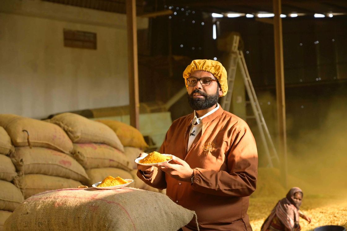 Fourth-generation proprietor at the Sangli warehouse, holding fresh turmeric powder beside stacked jute sacks